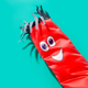 a red inflatable tube man with two eyes and a smiling mouth as well as some fringe hair